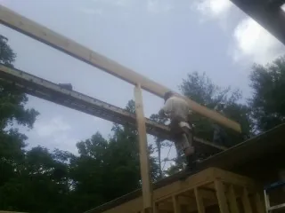 Carpenter setting a ridge beam over a new addition frame — Ice Dam Removal by Roofing Brothers in Warners