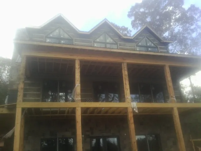 Dormers and porch framing on a large log home under construction — Roof Coating work by our crew in Warners