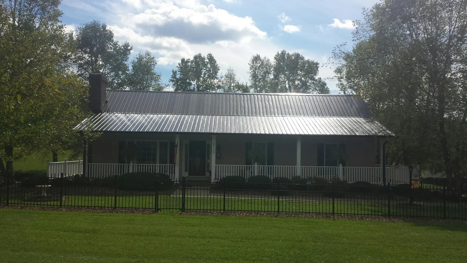 Gray metal roof on a brick ranch with a full width front porch — Gutter Guard Installation work by our crew in Warners