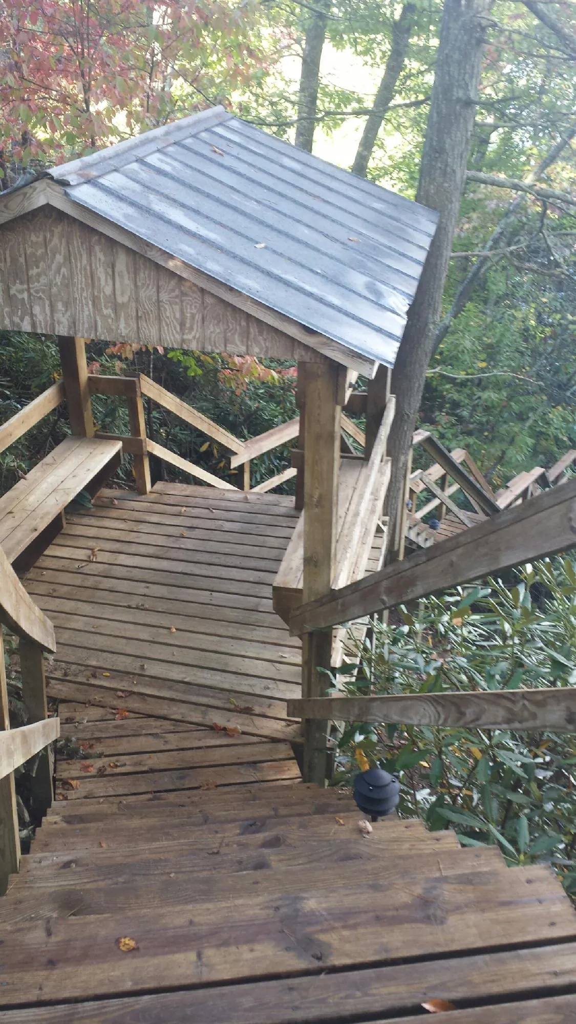 Metal roofed shelter over wooden steps on a wooded walkway — Skylight Repair & Installation work by our crew in Warners