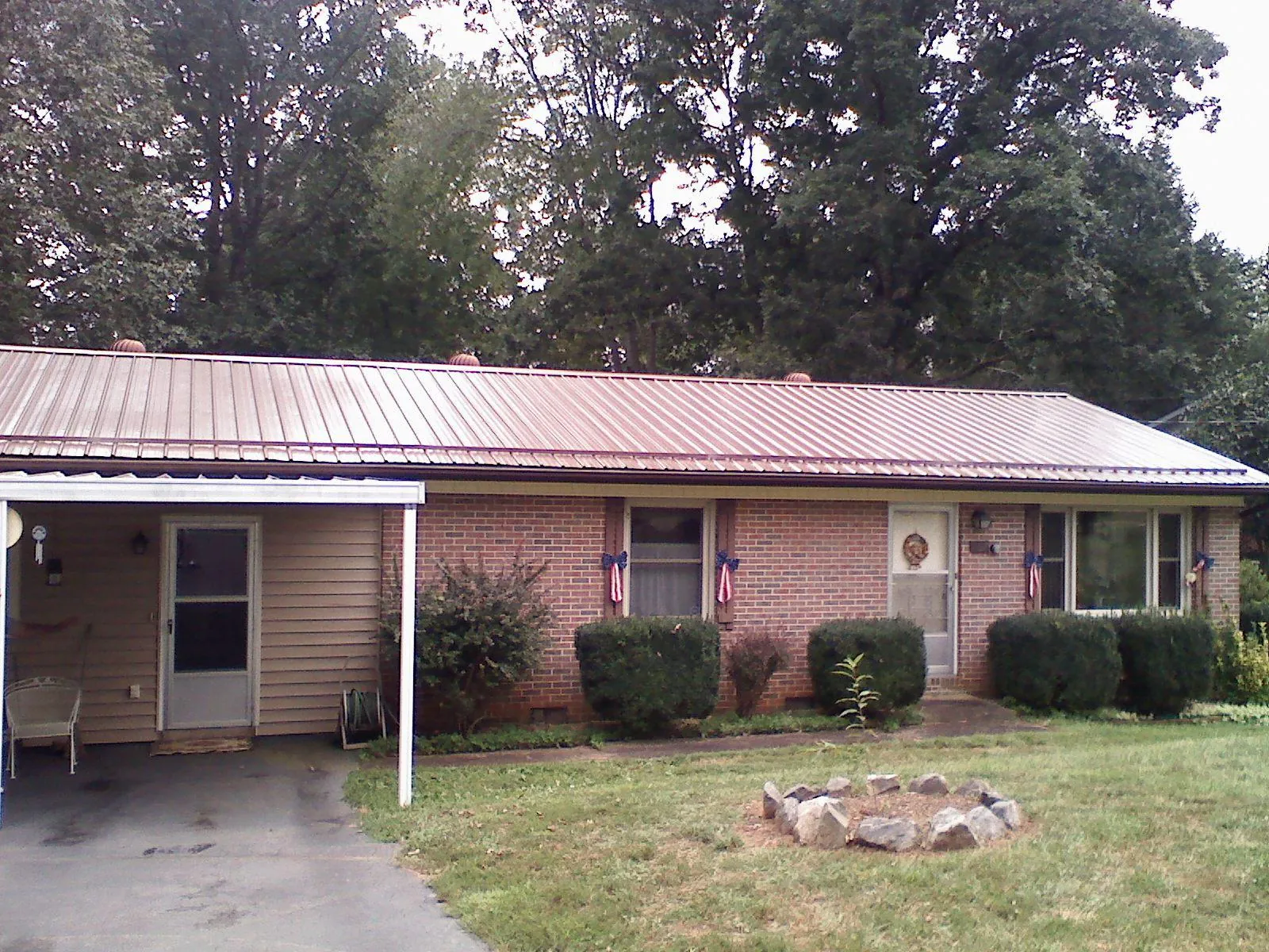 Bronze metal roof and carport on a brick ranch home — Roof Repair work by our crew in Warners